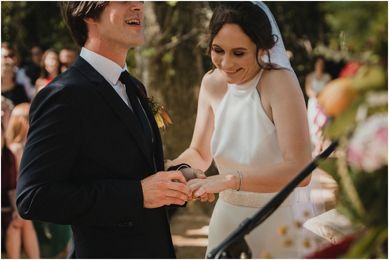 groom putting wedding ring on brides finger